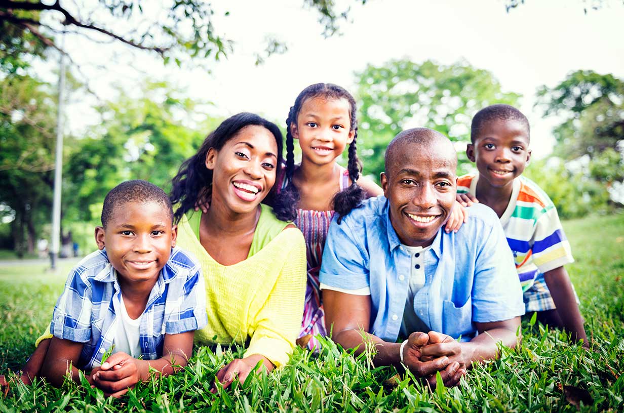  family with parents and three children posing on the grass outside